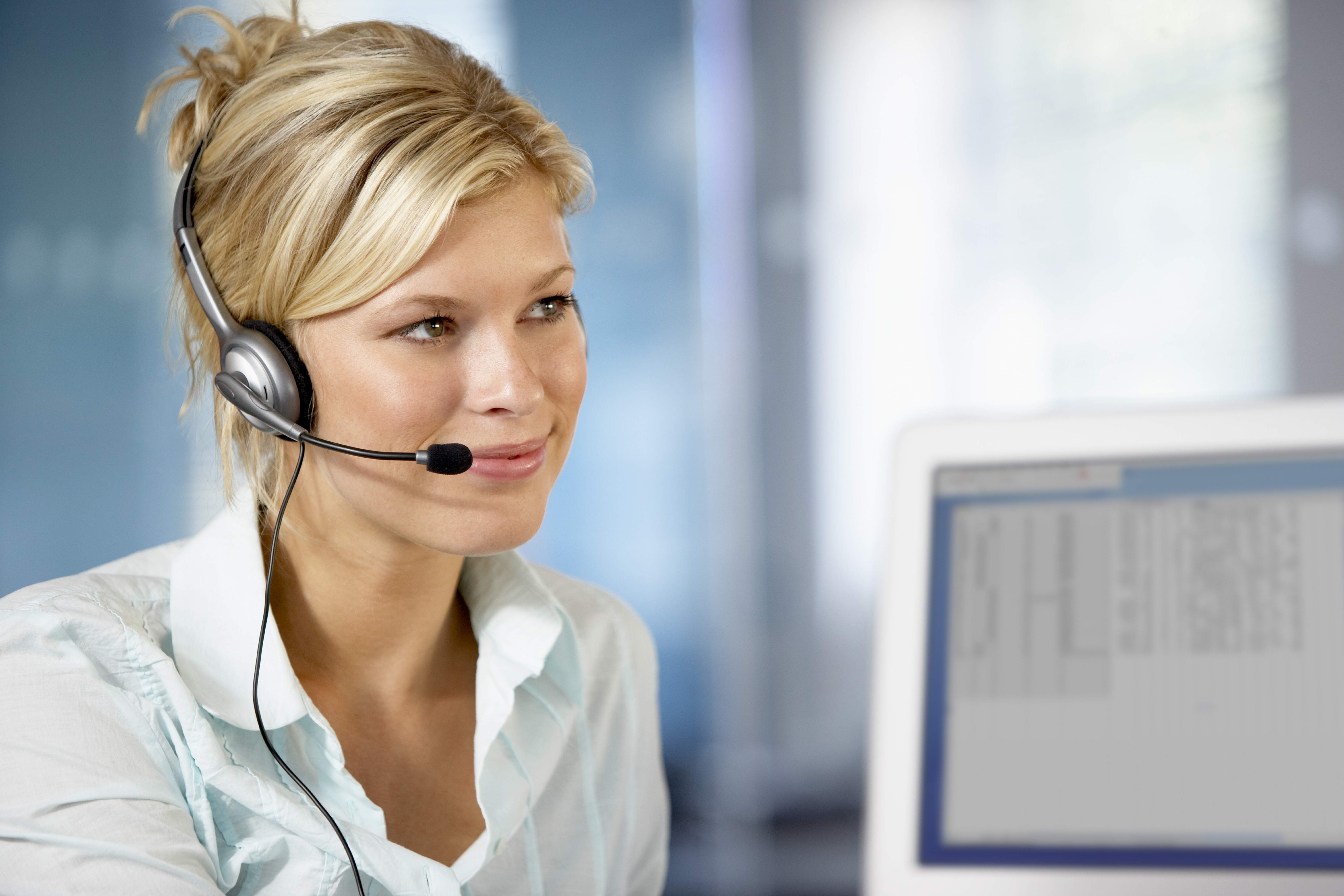 A woman wearing a headset and speaking into a microphone while seated at a desk